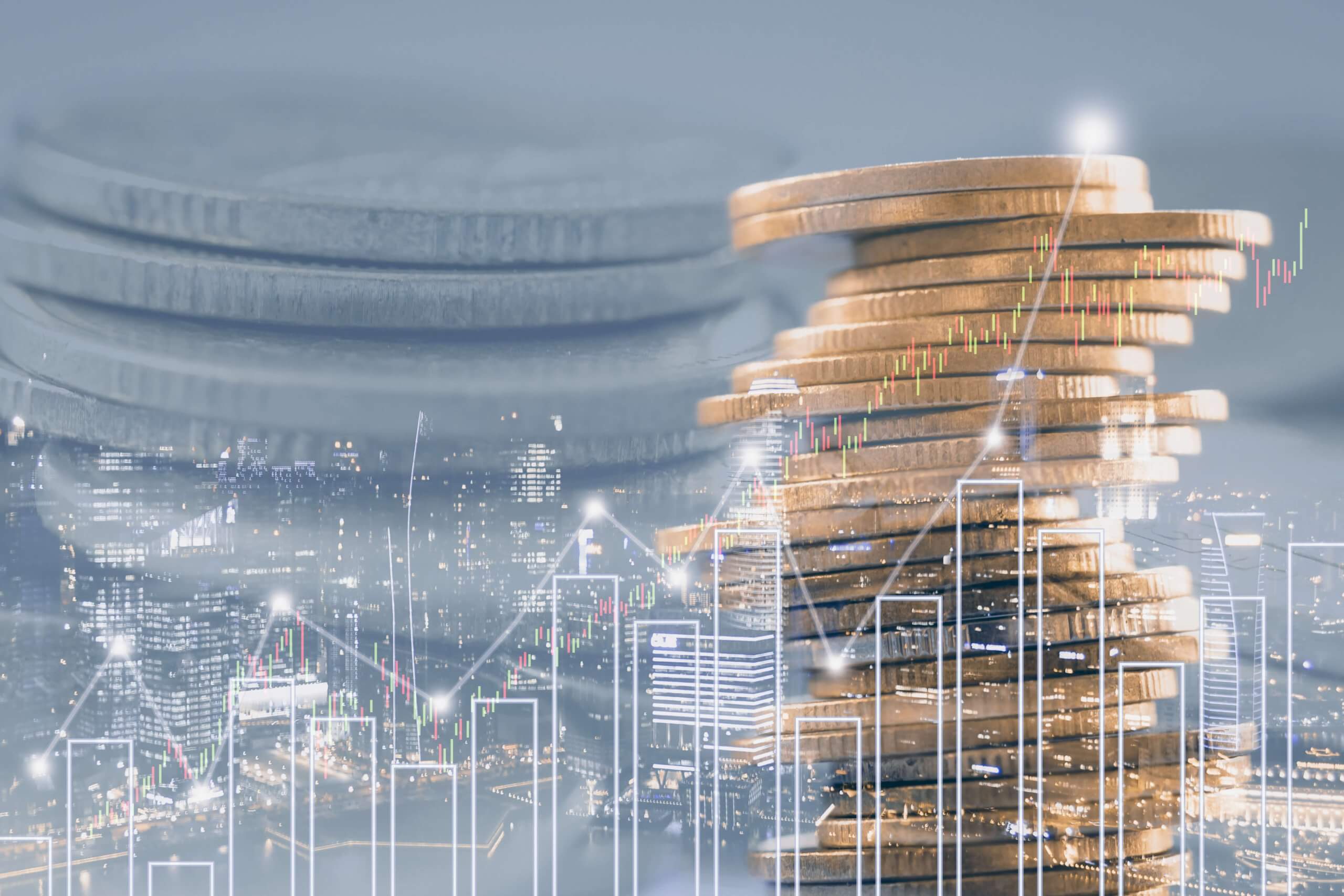 graph and coins stacked in front of a nighttime cityscape